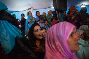 Mujer saharaui se divierte mirando a los bailarines en una fiesta de matrimonio que se lleva a cabo en el campamento. Campamento de refugiados Smara, cerca de Tindouf, Algeria.  2013