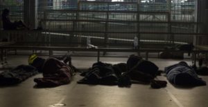 Varias personas duermen en sacos durante el encierro en el colegio Fructuós Gelabert de Barcelona. /JAIRO VARGAS