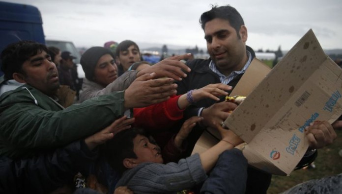 Inmigrantes, que esperaan cruzar la frontera entre Grecia y Macedonia, pelean por comida en un campo provisional cerca de Idomeni / MARKO DJURICA (REUTERS)